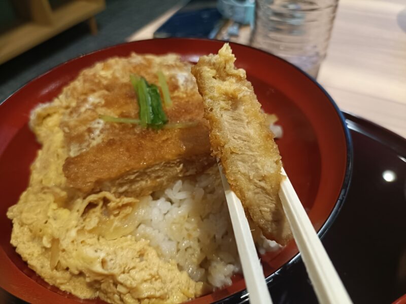 つばさ山温泉の食事処で食べるカツ丼のお肉を箸でつかむ