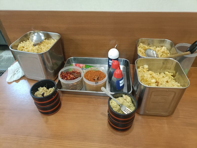 麺処綿谷高松店の無料薬味コーナーにある天かす、おろし生姜、粗めの鷹の爪